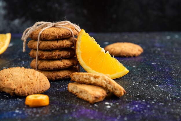 Cerrar foto de pila de galletas caseras con una rodaja de naranja sobre la superficie del espacio.