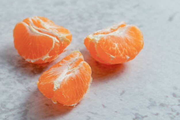 Cerrar foto de rodajas de mandarina orgánica sobre superficie gris.