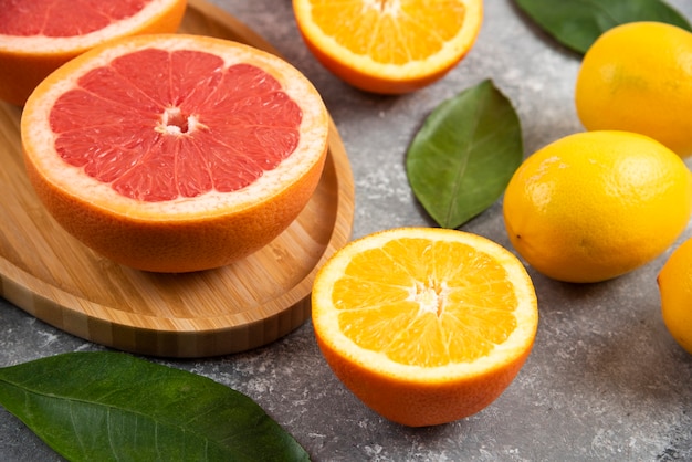 Cerrar foto de rodajas de naranja y pomelo sobre superficie gris.