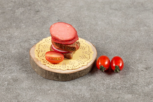 Cerrar foto de sándwich casero con tomate sobre tabla de madera.