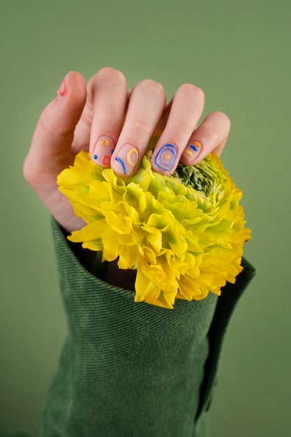 Cerrar hermosa manicura y flor amarilla