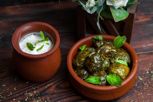 Cerrar hojas de uva dolma rellenas de carne y arroz con salsa de crema agria en una mesa de madera oscura. cocina tradicional de europa oriental y asiática