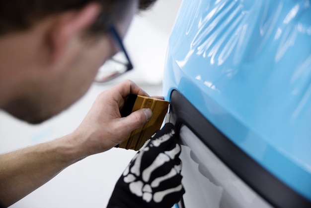 Cerrar hombre envolviendo coche con cubierta azul