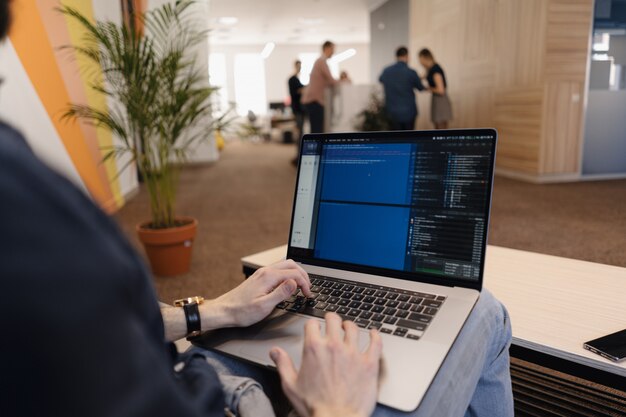 Cerrar hombre escribiendo código en la computadora portátil