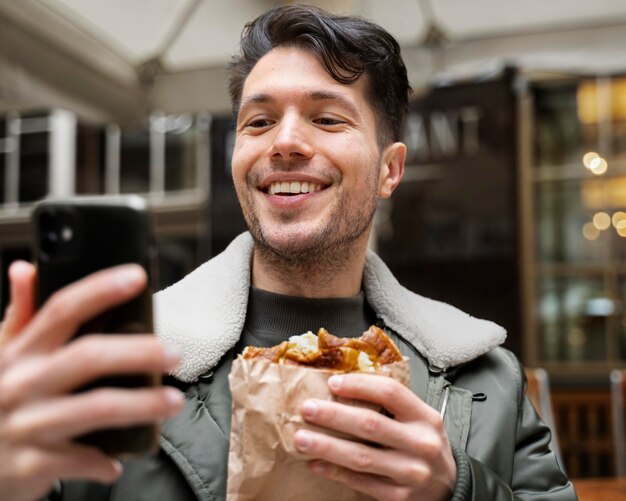 Cerrar hombre sonriente con comida y teléfono