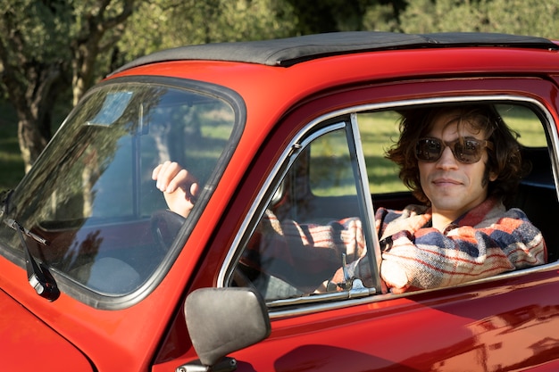 Cerrar hombre sonriente conduciendo coche rojo