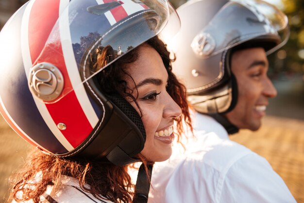 Cerrar imagen de la feliz pareja africana monta en moto moderna en la calle