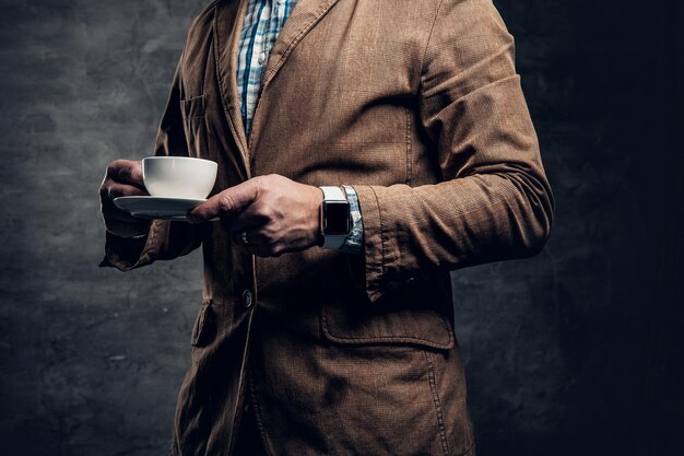 Cerrar imagen de macho barbudo pelirrojo sostiene una taza de café sobre fondo gris.