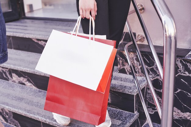 Cerrar joven llevando bolsas de compras mientras camina por las escaleras después de visitar las tiendas.