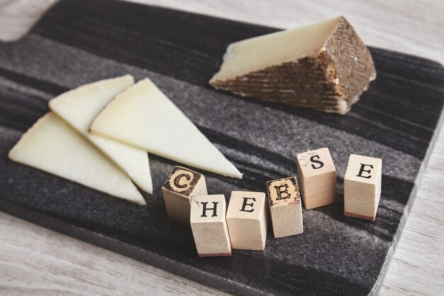 Cerrar el lado enfocado letras queso adelante queso de cabra desenfocado en tablero de piedra de mármol aislado en mesa de madera en blanco