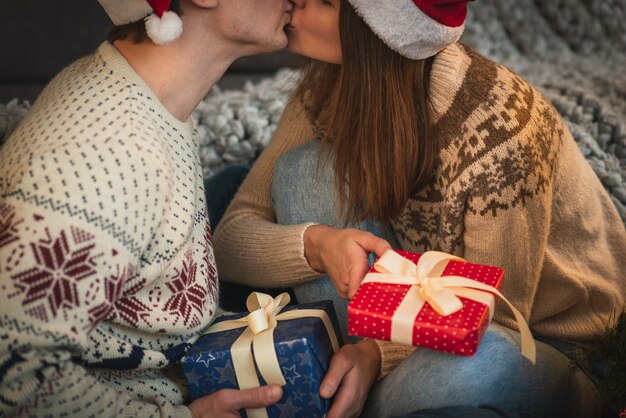 Cerrar linda pareja con regalos de Navidad besándose