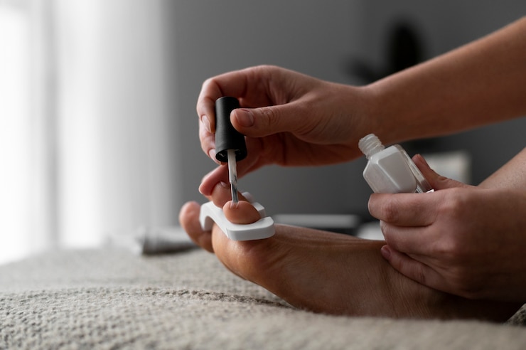 Foto gratuito cerrar la mano aplicando esmalte de uñas en las uñas de los pies