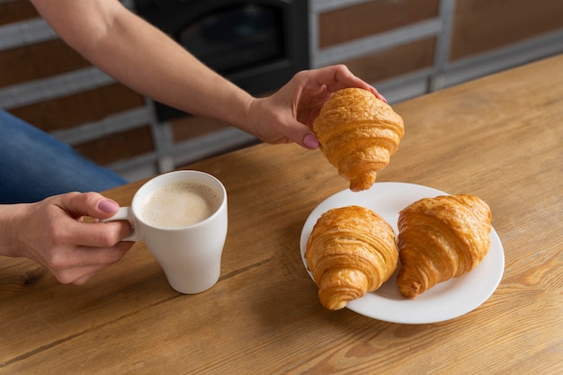 Foto gratuita cerrar mano con croissant y café