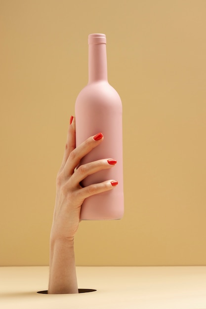 Foto gratuita cerrar mano sujetando botella rosa