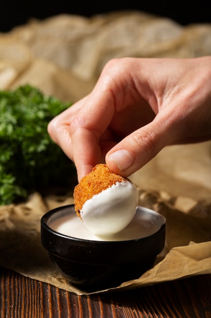 Cerrar mano sujetando croqueta de comida con salsa