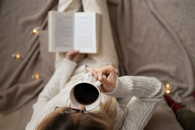 Cerrar mano sujetando libro y taza de café