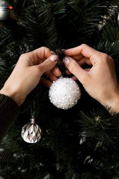 Cerrar las manos decorando el árbol de navidad