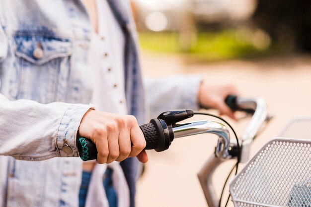 Cerrar las manos de la mujer en el manillar de la bicicleta