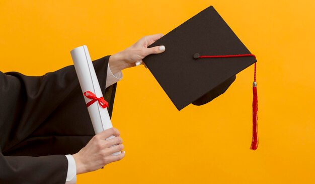 Cerrar manos sosteniendo diploma y gorra