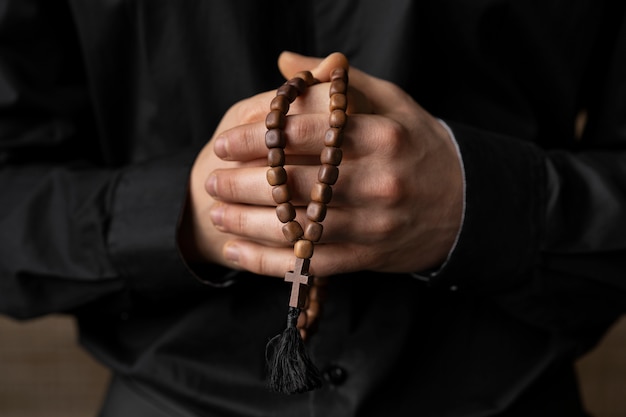 Cerrar manos sosteniendo rosario