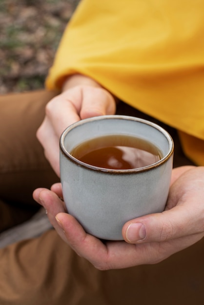 Cerrar las manos sosteniendo la taza de té