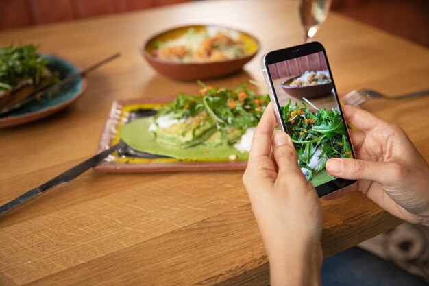 Cerrar las manos tomando fotos de comida