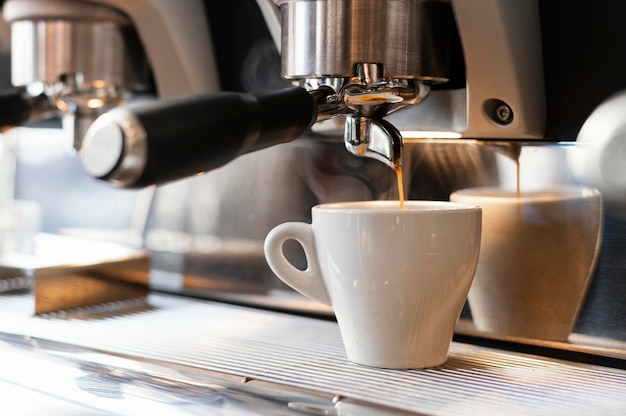 Cerrar máquina vertiendo café en taza