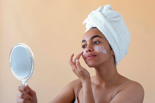 Cerrar mujer aplicando crema facial