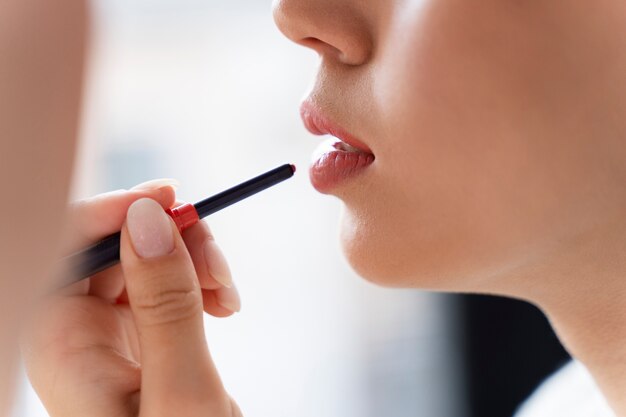 Cerrar mujer aplicando lápiz labial