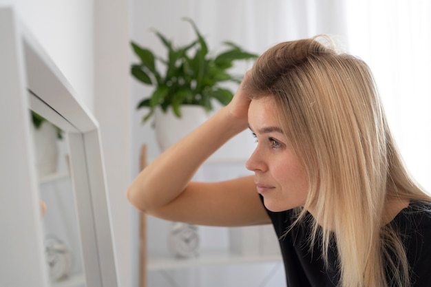 Cerrar mujer con caspa mirando en el espejo