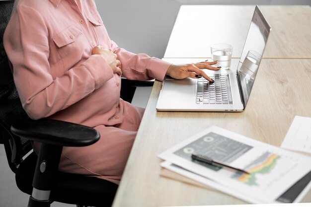 Cerrar mujer embarazada escribiendo en la computadora portátil