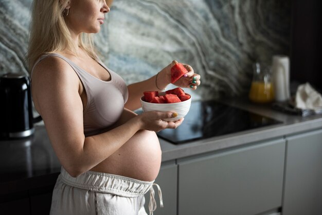 Cerrar mujer embarazada sosteniendo frutero