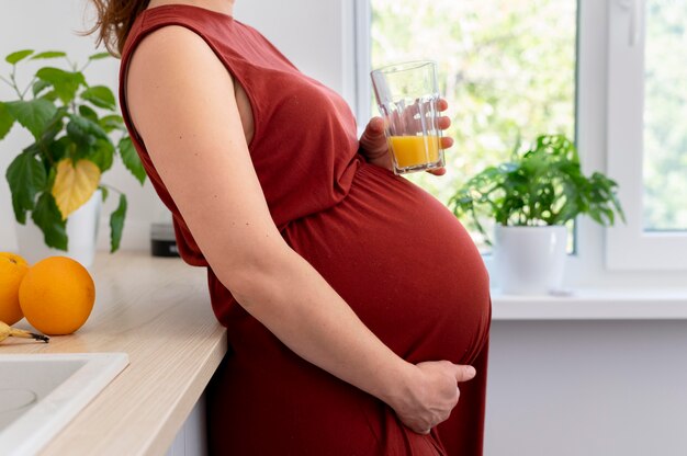 Cerrar mujer embarazada sosteniendo vaso de jugo