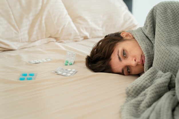 Cerrar mujer enferma en la cama con pastillas