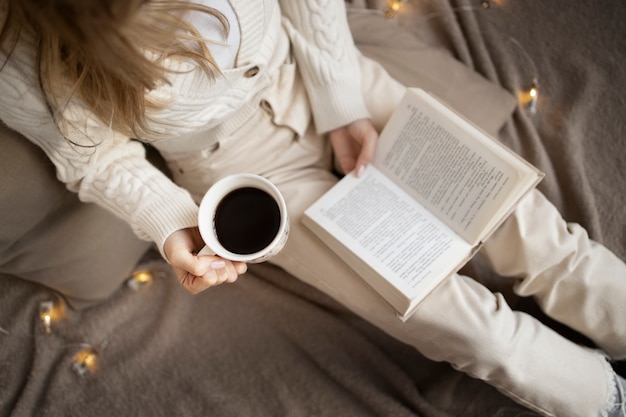 Cerrar mujer leyendo en casa con café