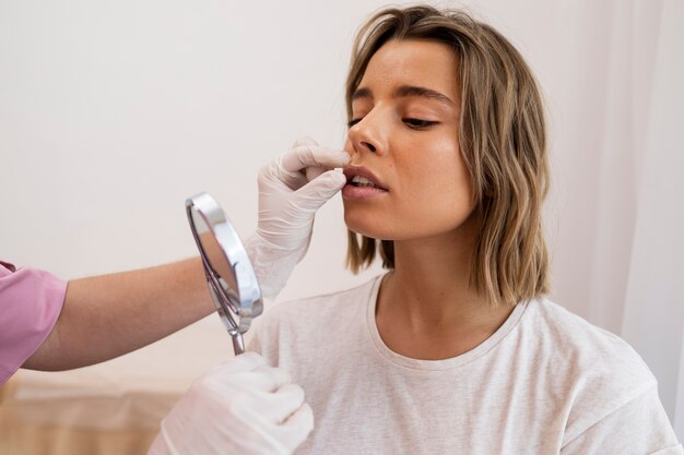 Cerrar mujer mirándose en el espejo después de relleno de labios