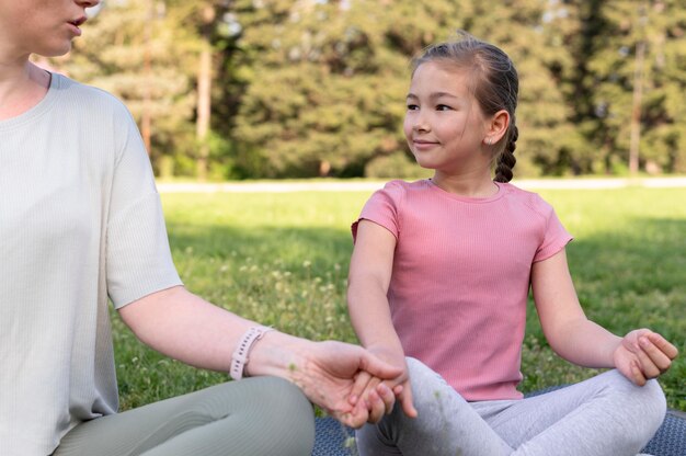 Cerrar mujer y niña meditando