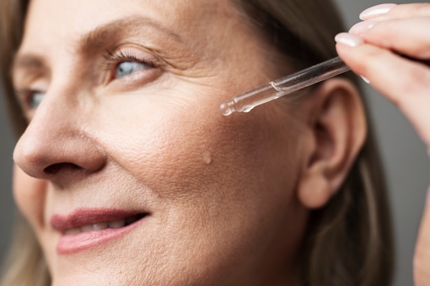 Cerrar mujer senior sonriente usando suero