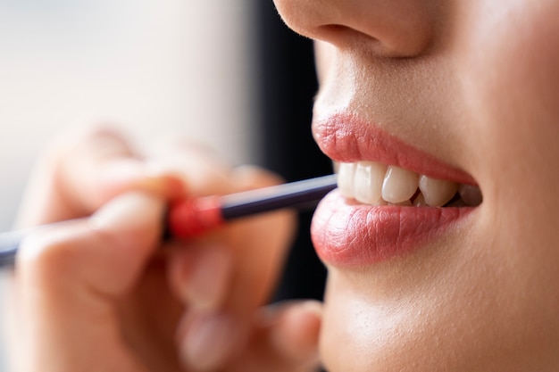 Cerrar mujer sonriente aplicando lápiz labial