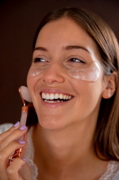 Cerrar mujer sonriente con parches en los ojos