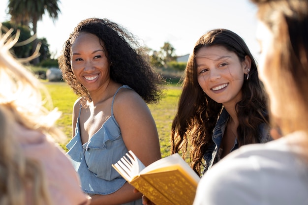 Cerrar mujeres felices con libros al aire libre