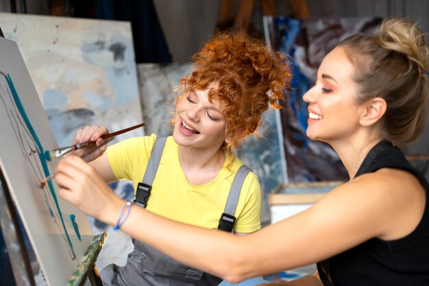 Cerrar mujeres pintando sobre lienzo