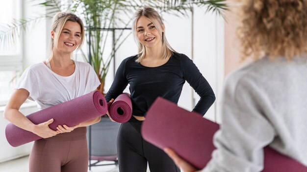 Cerrar mujeres sonrientes con colchonetas de yoga
