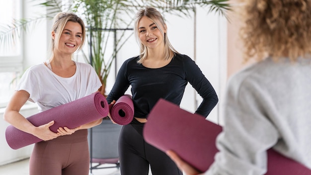 Cerrar mujeres sonrientes con colchonetas de yoga