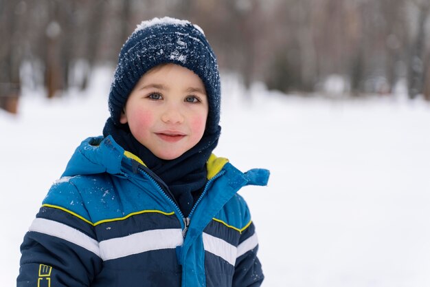 Cerrar n niño feliz jugando en la nieve.