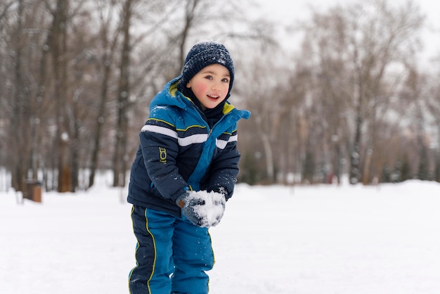 Cerrar n niño feliz jugando en la nieve.