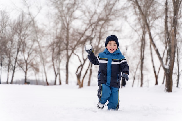 Cerrar n niño feliz jugando en la nieve.