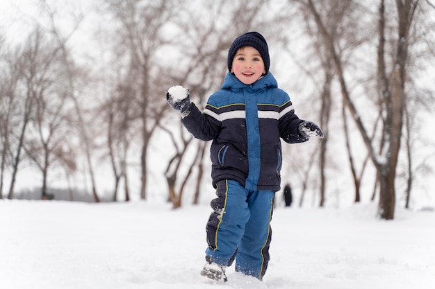 Cerrar n niño feliz jugando en la nieve.