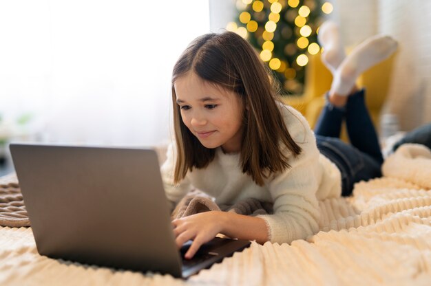 Cerrar niña escribiendo en la computadora portátil
