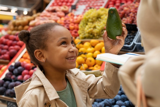 Cerrar niña sonriente sosteniendo aguacate